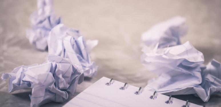 crumpled up paper next to a notebook