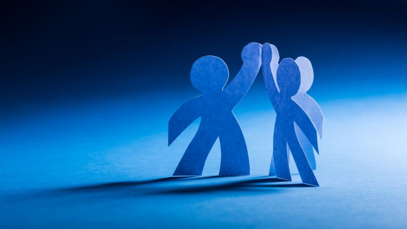 Two paper figures with arms upraised give a high five