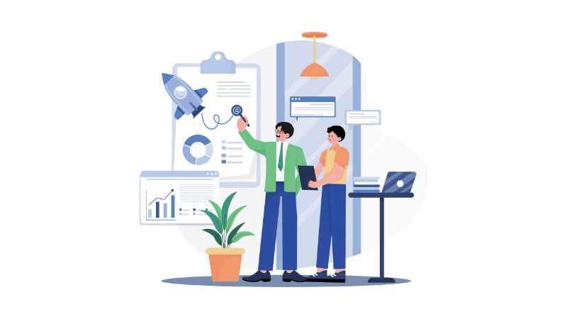 Two people stand in an office surrounded by items one might use in project anagement