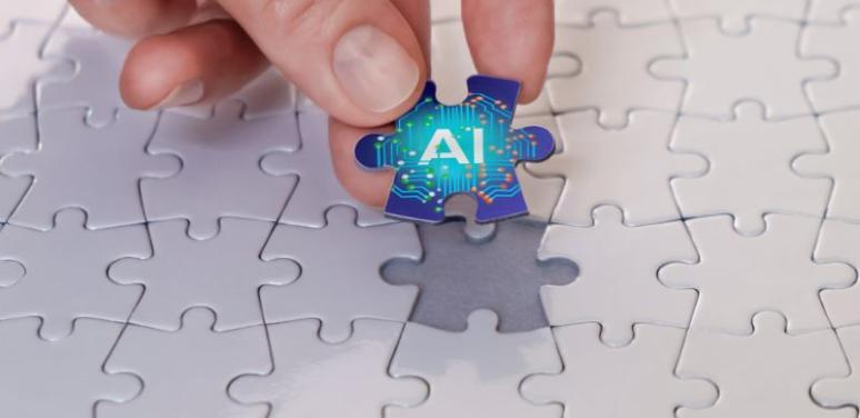 Decorative image showing a solid white puzzle except for one piece that is being lifted by a hand. That piece shows the text AI on a blue field.