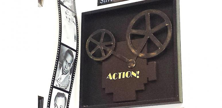 Image of film reel and black camera silhouette that says "action" 